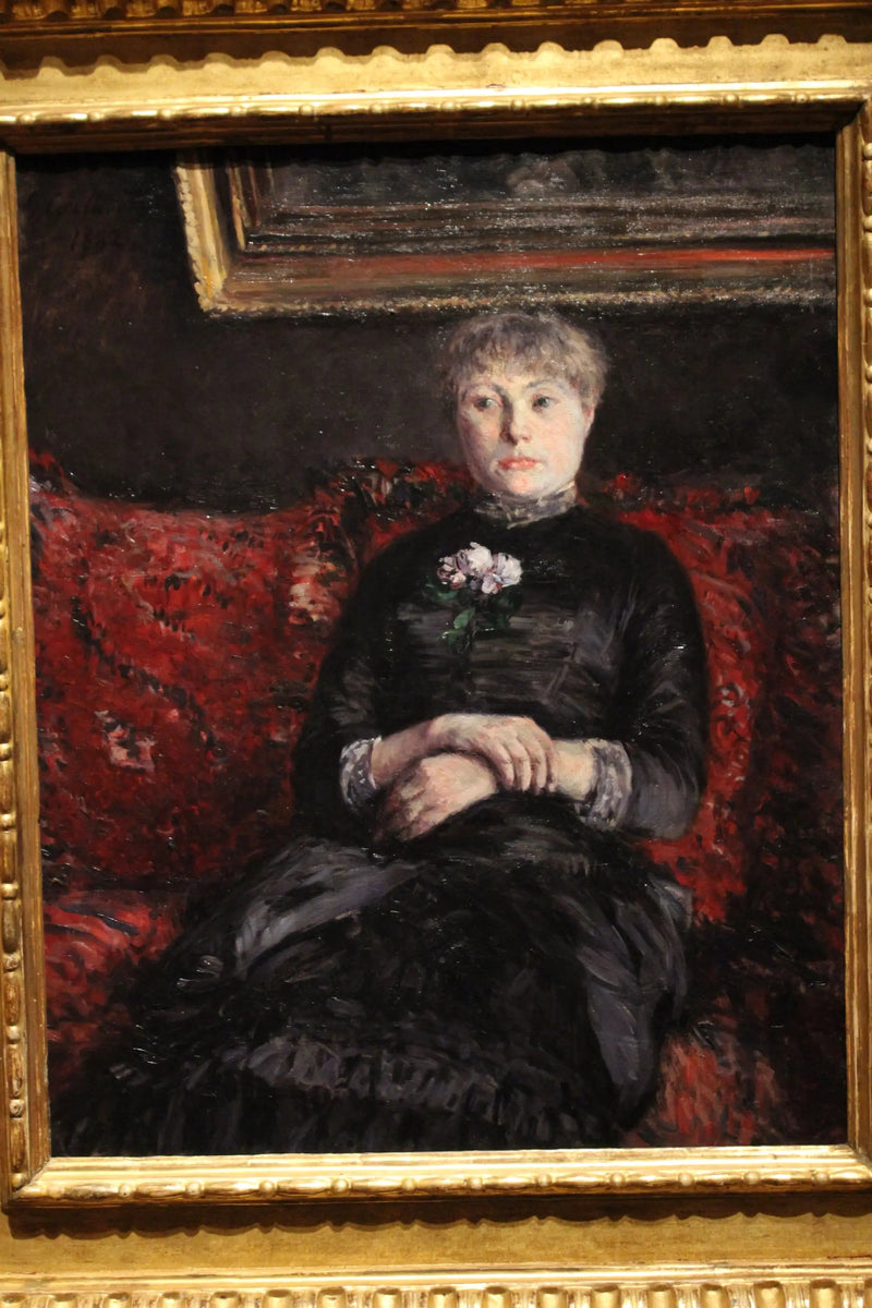 Kvinne som sitter på en sofa med røde blomster - Gustave Caillebotte